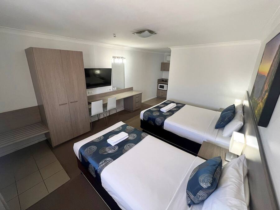 A hotel room with two beds, a TV, a desk, and a wardrobe.
