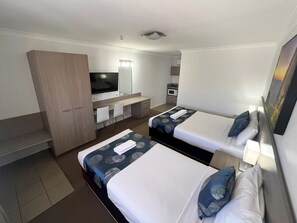 A hotel room with two beds, a TV, a desk, and a wardrobe. - Adelong Motel (Narrabri)