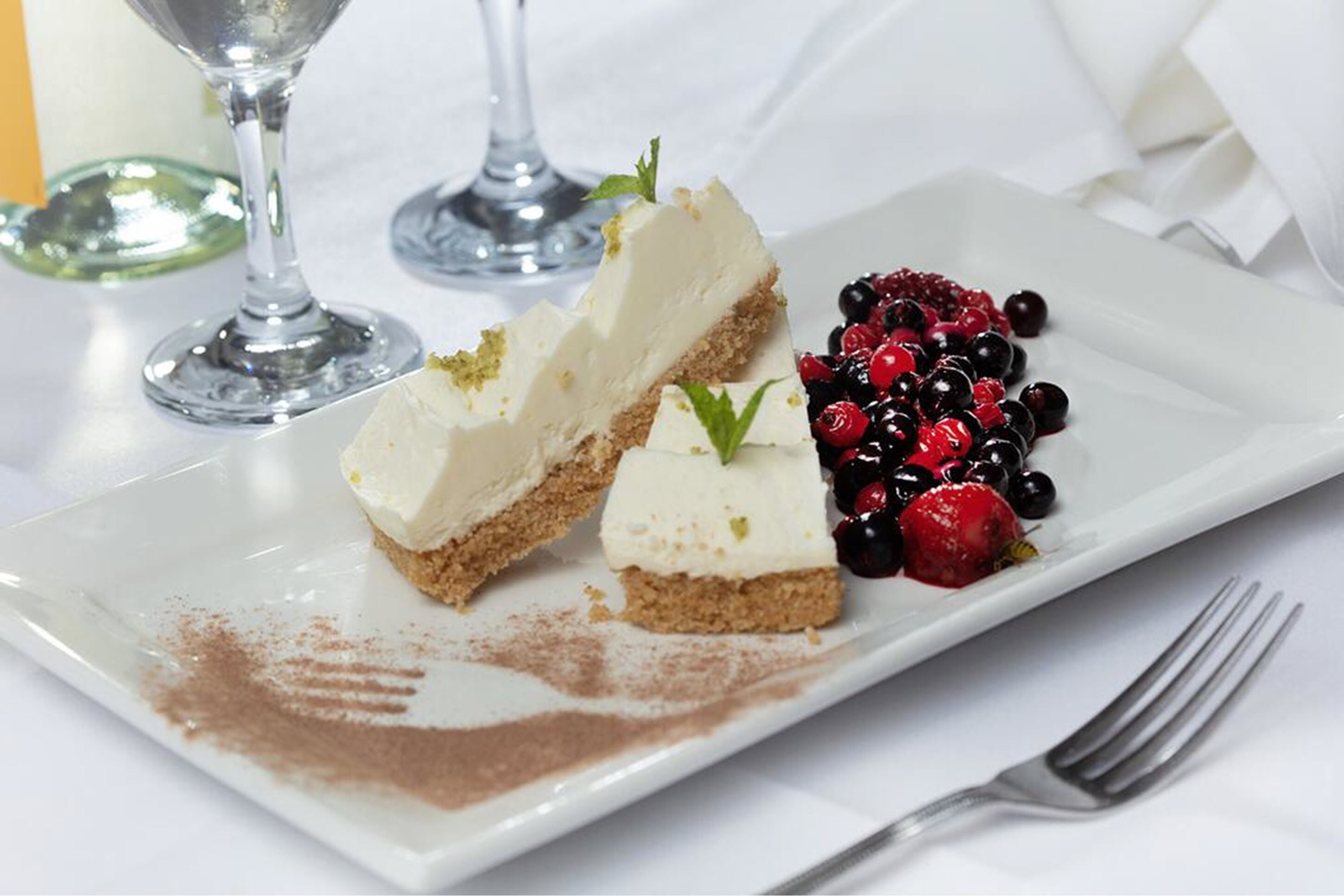 A dessert plate with cheesecake and berries on a white plate.