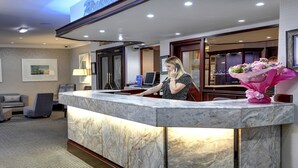 A hotel reception area with a marble counter, framed artwork on the walls, and a seating area with patterned sofas.