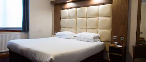 A hotel room with a large bed, a wooden headboard, a nightstand, and a chair.