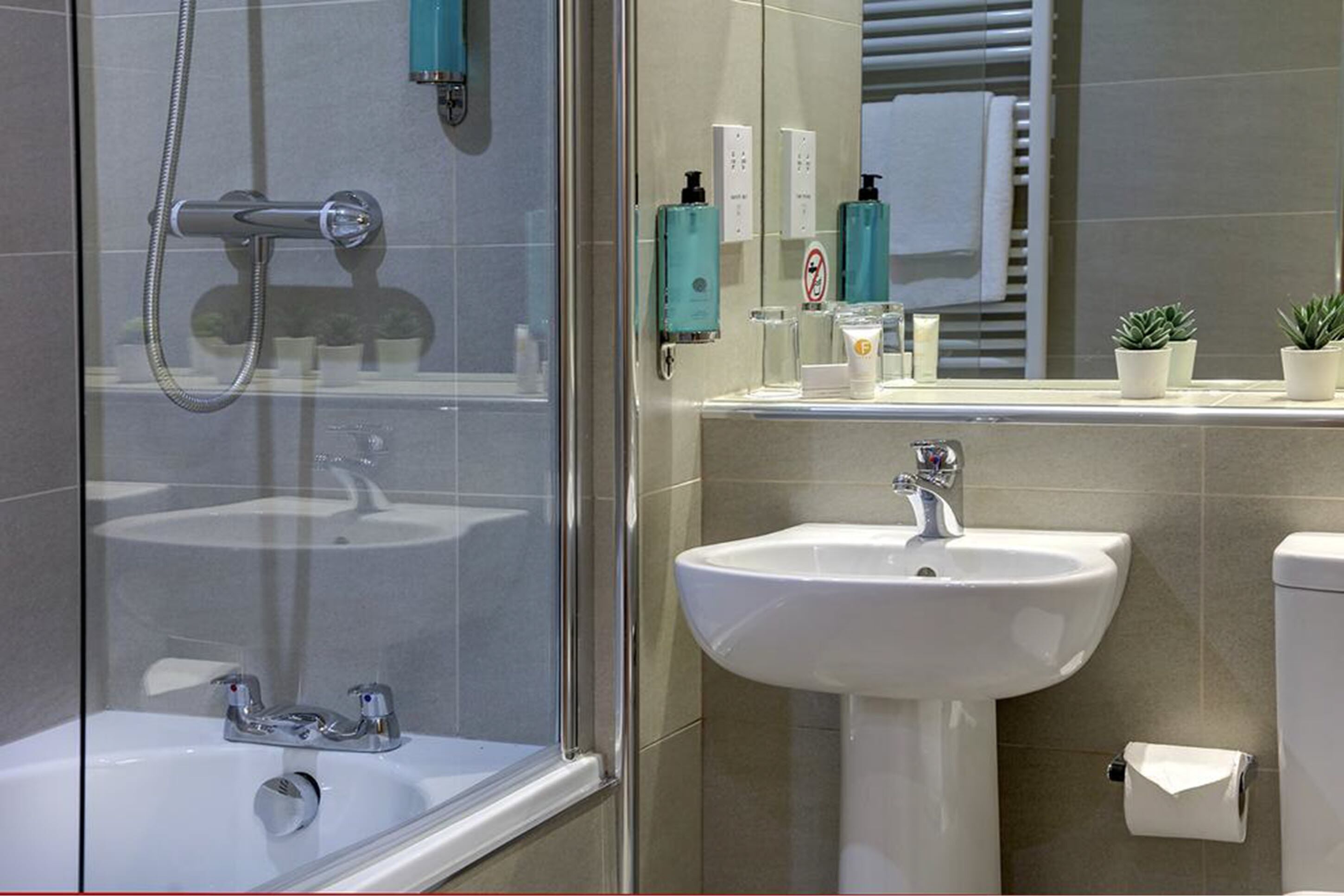Une salle de bain moderne avec une douche à parois de verre, un lavabo blanc et des toilettes.