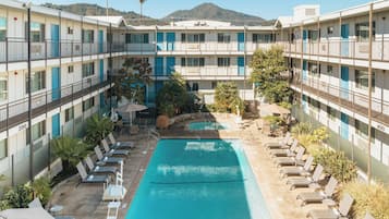 Una piscina al aire libre, sombrillas, sillones reclinables de piscina