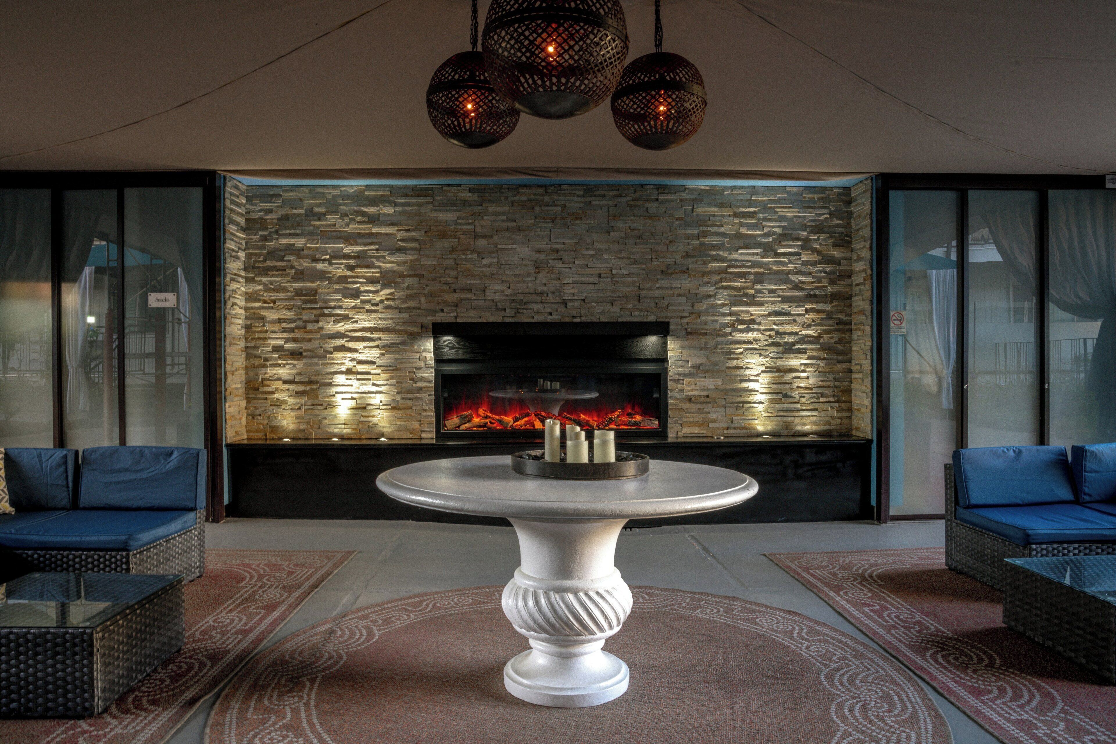 A modern living room with a stone wall, a fireplace, a round table, and two sofas.