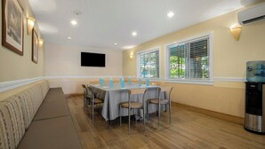 Un comedor con una mesa larga, sillas, un sofá y un televisor montado en la pared.