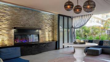 A modern outdoor seating area with a stone wall, a fireplace, and a dining table.