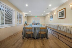 A conference room with a long table, chairs, a bench, and a view of a balcony. - Marin Suites Hotel (Corte Madera)