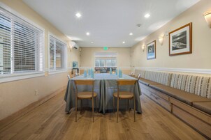 Uma sala de conferências com uma mesa comprida, cadeiras, um banco e vista para uma varanda.
