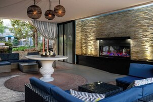 Un patio exterior con una mesa redonda, sofás y una pared de piedra con chimenea.