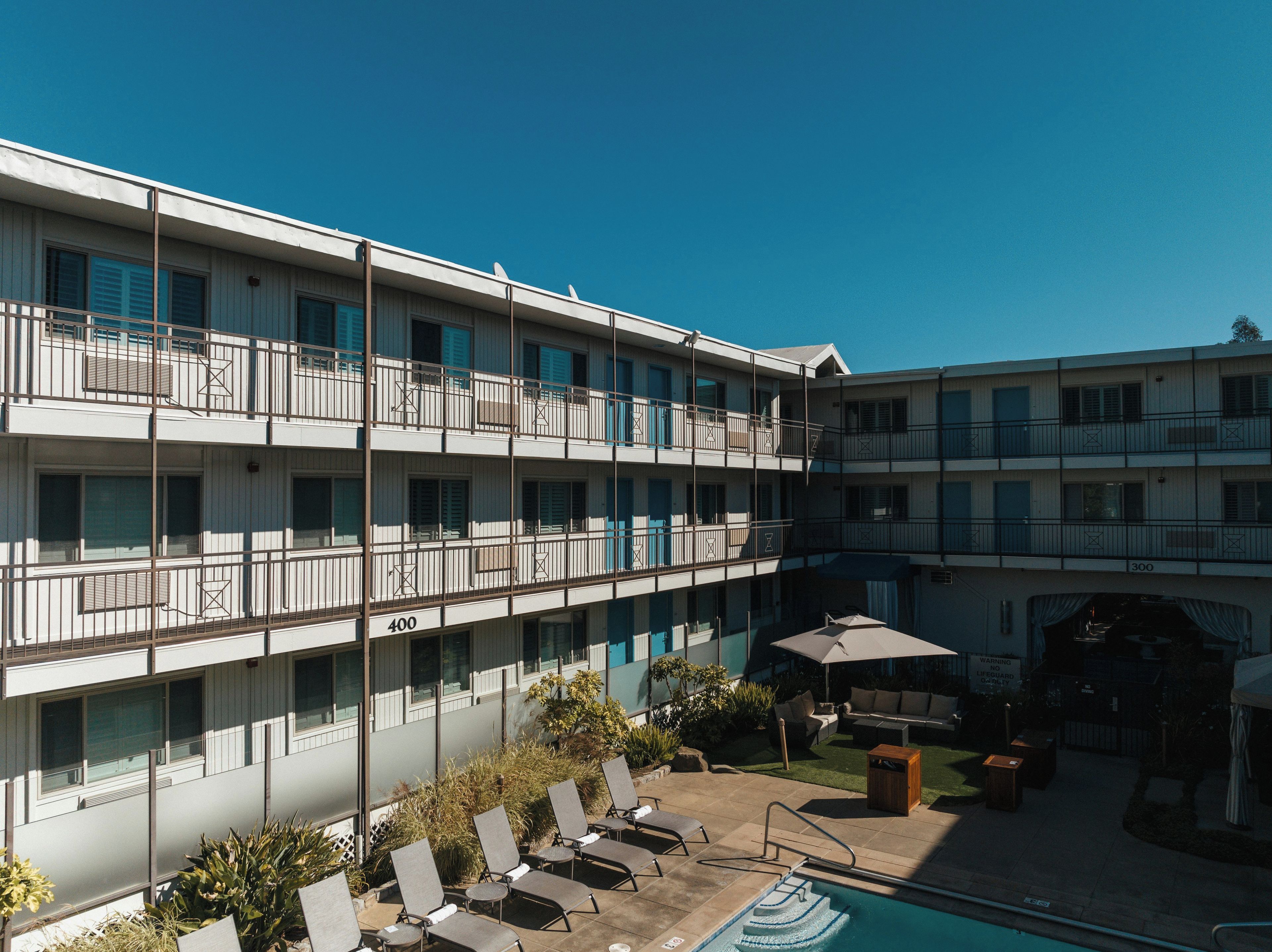 A multi-story hotel with balconies, a swimming pool, and outdoor seating.