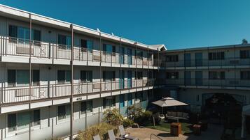 A multi-story hotel with balconies, a swimming pool, and outdoor seating.