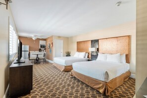 A hotel room with two beds, a desk, a chair, a television, and a ceiling fan. - Marin Suites Hotel (Corte Madera)