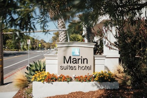 Señal del Hotel Marin Suites, con vista despejada a la carretera y la vegetación circundante.