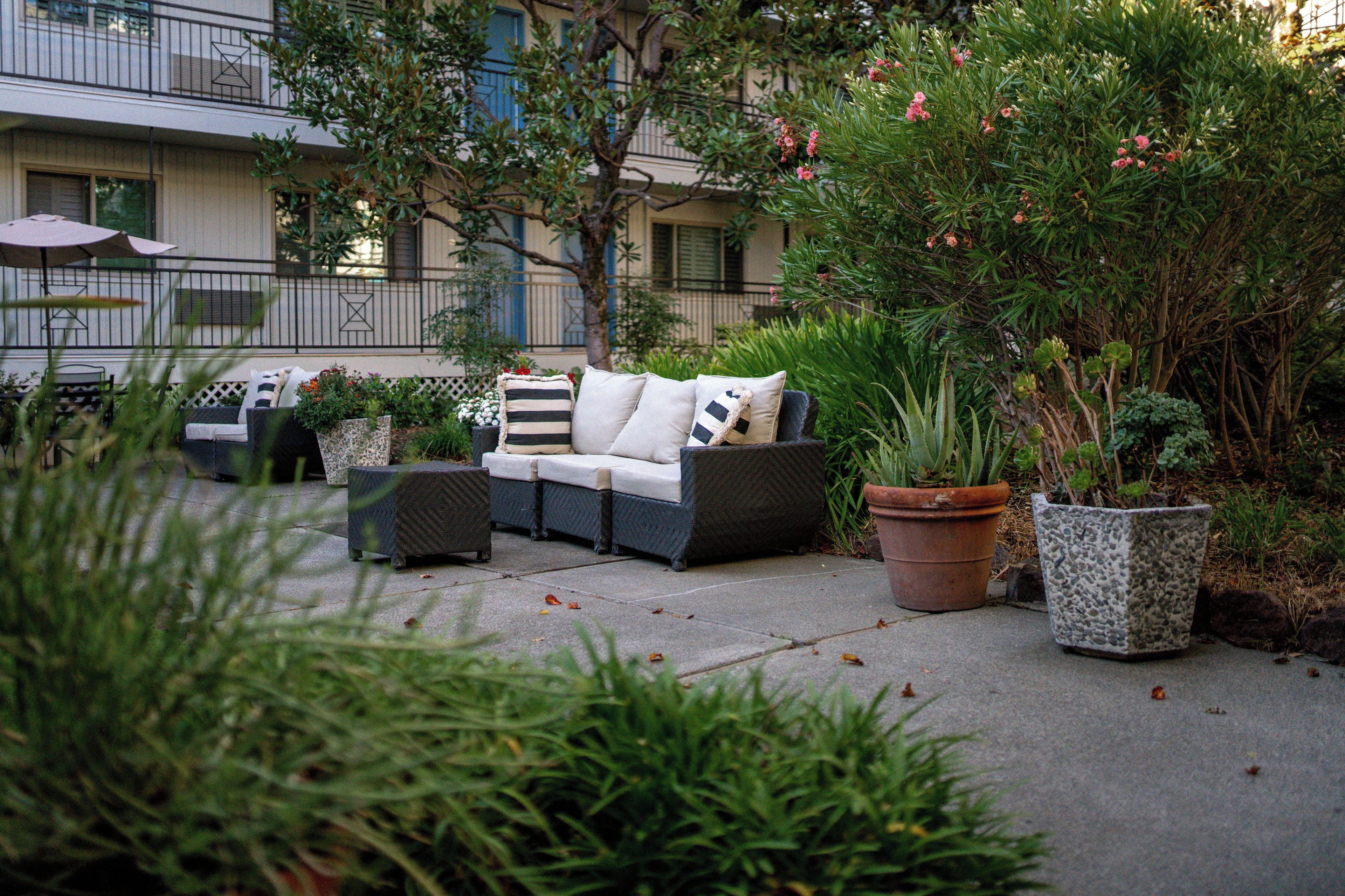 Un espace extérieur aménagé avec un canapé, des fauteuils et des jardinières.