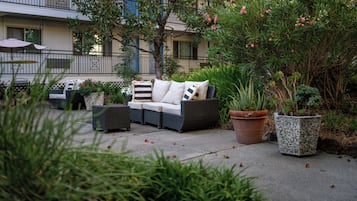 Un espace extérieur aménagé avec un canapé, des fauteuils et des jardinières.