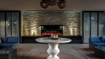 Un salon moderne avec un mur en pierre, une cheminée, une table ronde et deux canapés.