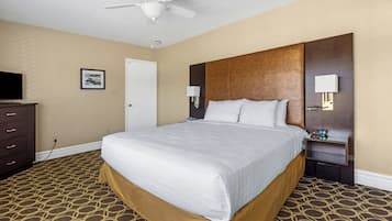 Une chambre d’hôtel équipée d’un lit, d’une commode, d’une télévision et d’un ventilateur de plafond.