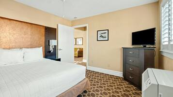 A hotel room with a bed, a TV, a dresser, and a patterned carpet.