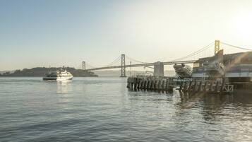 A ferry crossing a bridge over calm water with a cityscape in the background.