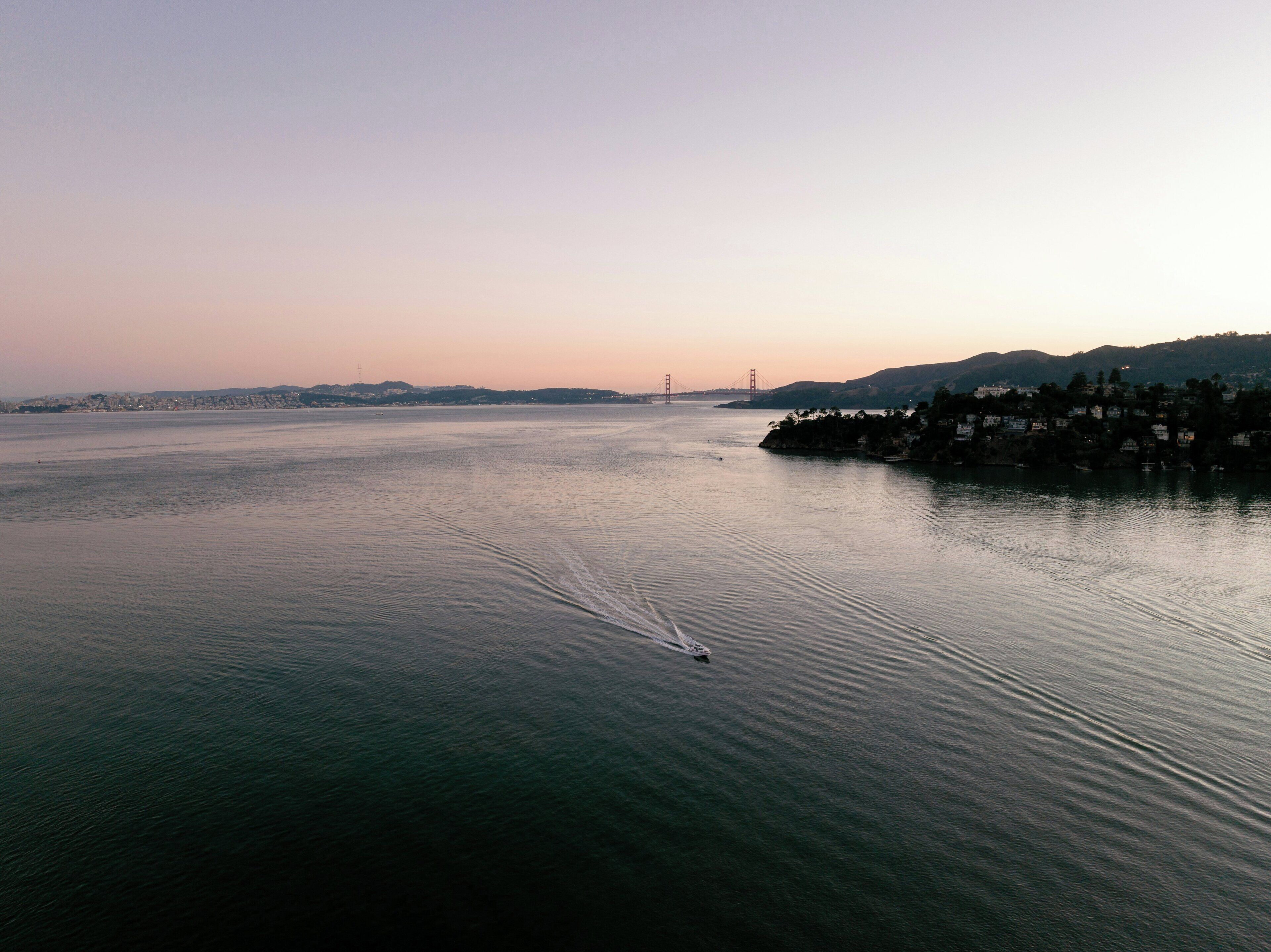 A large body of water with a bridge in the distance and a shoreline with buildings.
