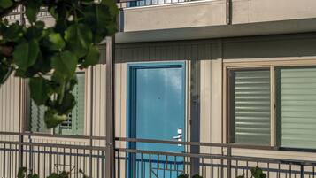 A multi-story building with balconies, a blue door, and a window with a geometric pattern.