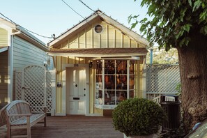 A building with a porch, a wooden bench, a potted plant, and a tree. - Marin Suites Hotel (Corte Madera)
