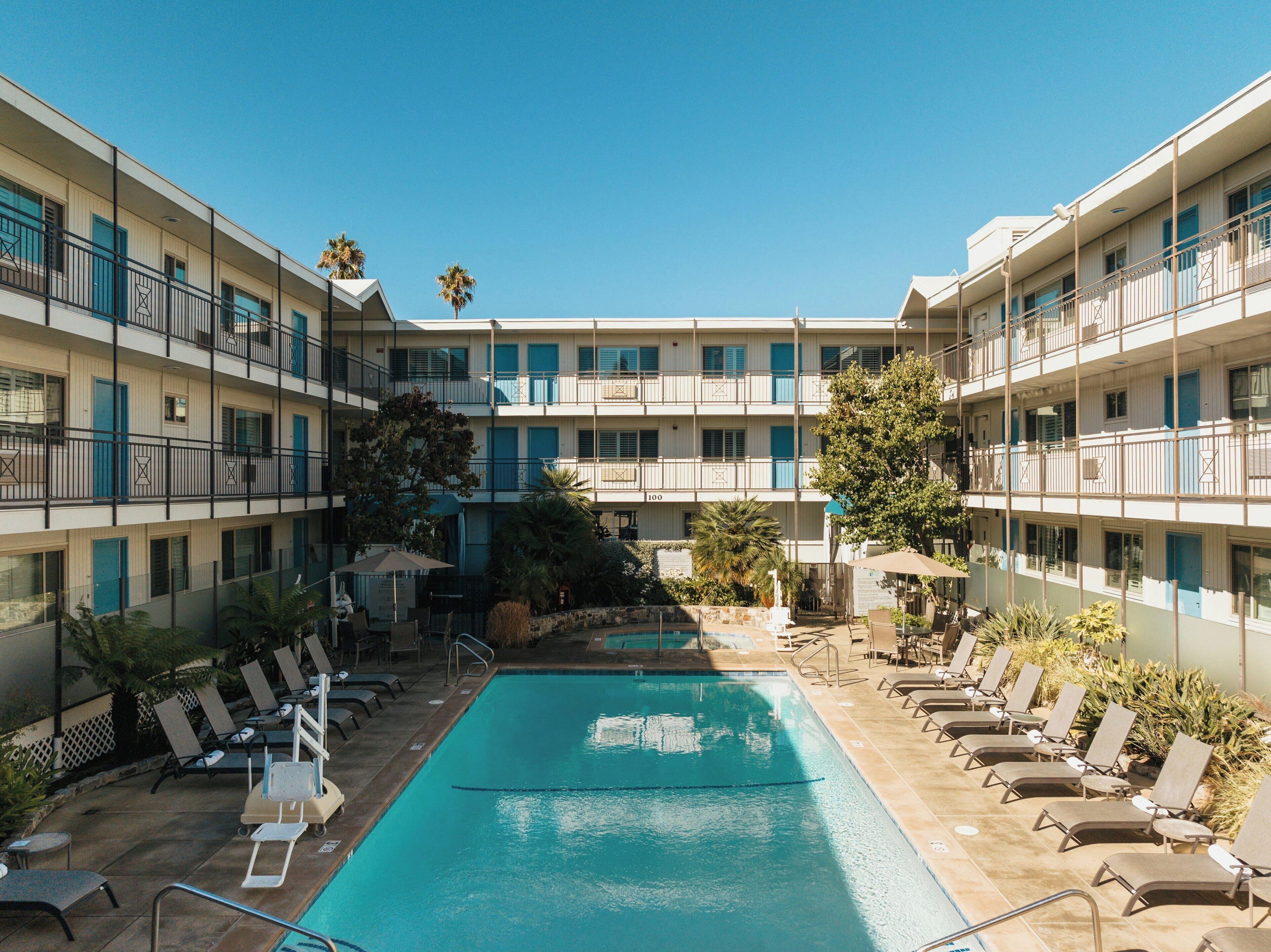 Una piscina al aire libre, sombrillas, sillones reclinables de piscina