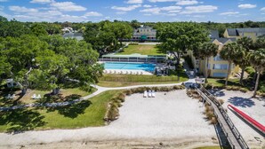 A resort with a swimming pool, beach area, and a dock.