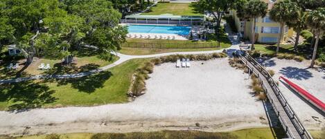 A resort with a swimming pool, beach area, and a dock.