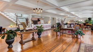 A spacious lobby with a grand staircase, wooden flooring, and multiple seating areas.