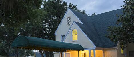 A two-story house with a steeply pitched roof, a dormer window, and a covered porch.