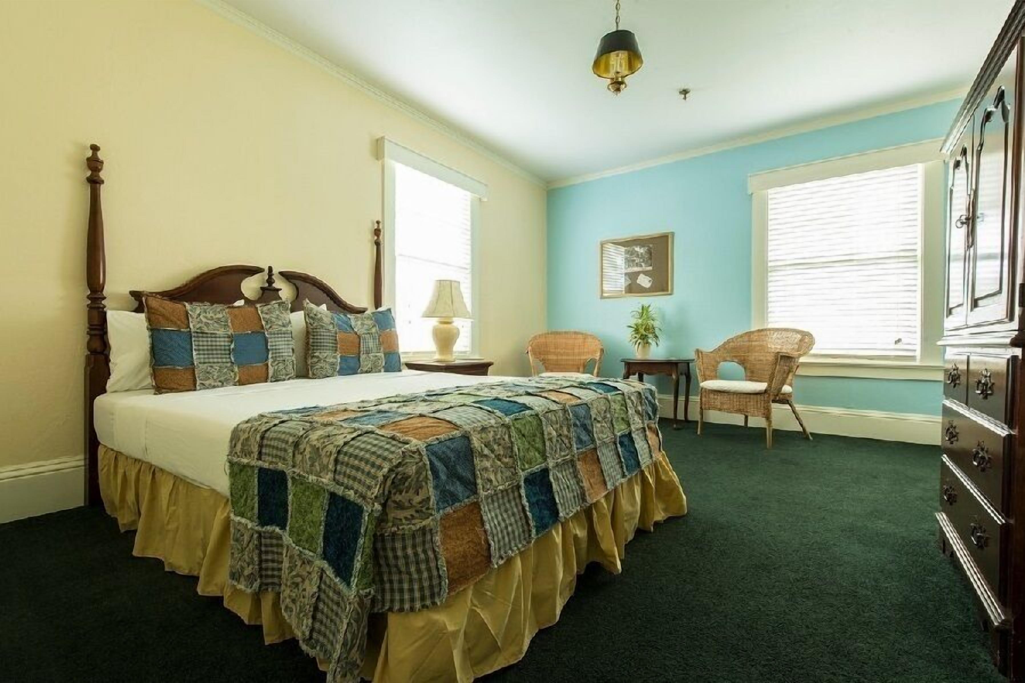 A bedroom with a bed, a chair, a dresser, and a window.