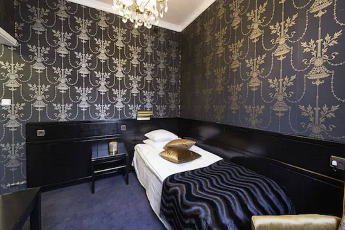 A bedroom with a large bed, a nightstand, a dresser, and a chandelier.