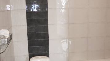 Un baño con inodoro, bañera y soporte para papel higiénico.