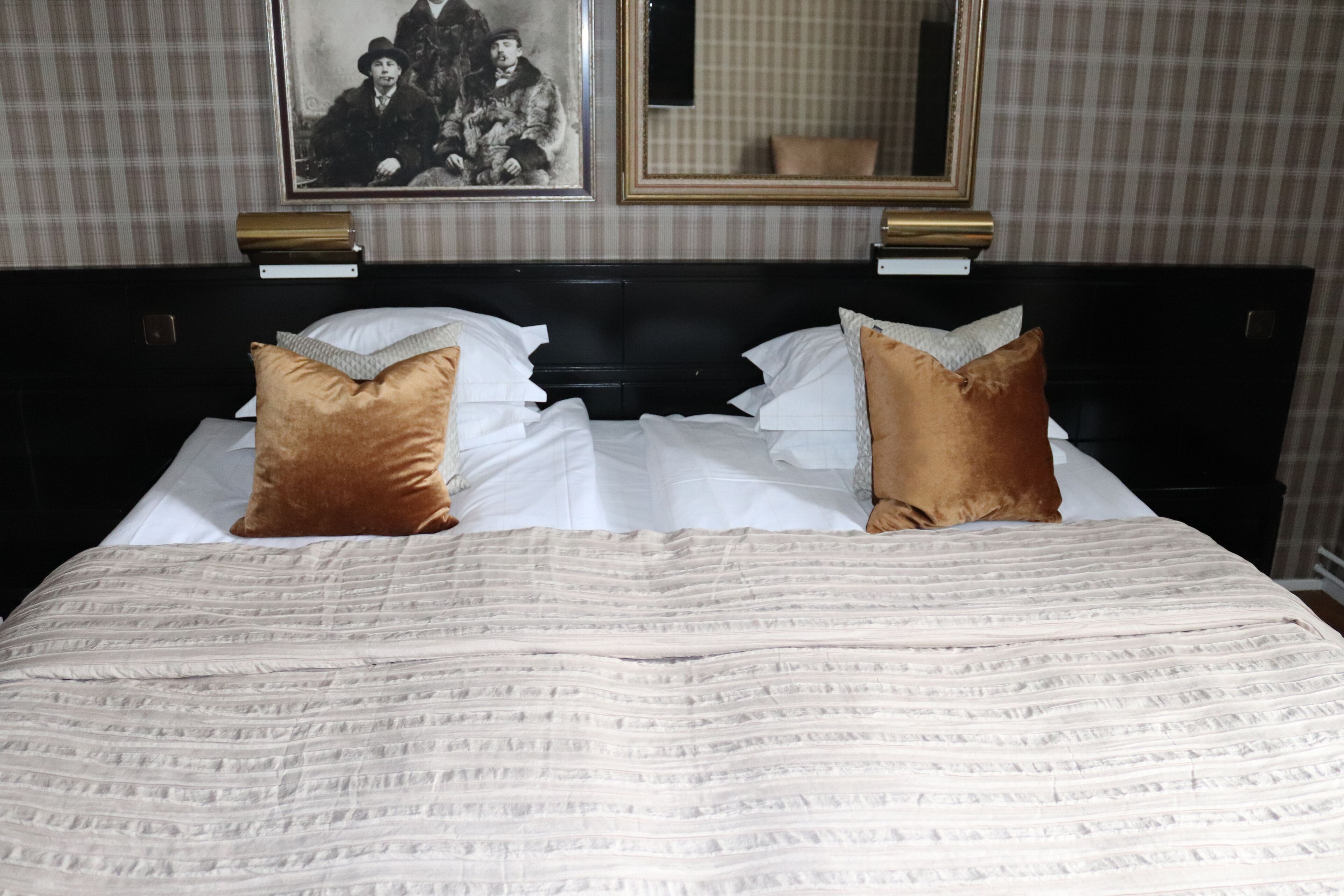 Cama bem arrumada com colcha listrada e dois travesseiros decorativos.