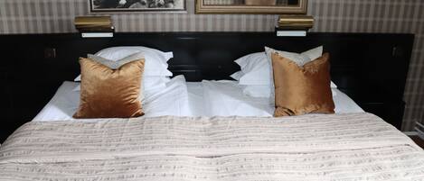 Cama bem arrumada com colcha listrada e dois travesseiros decorativos.
