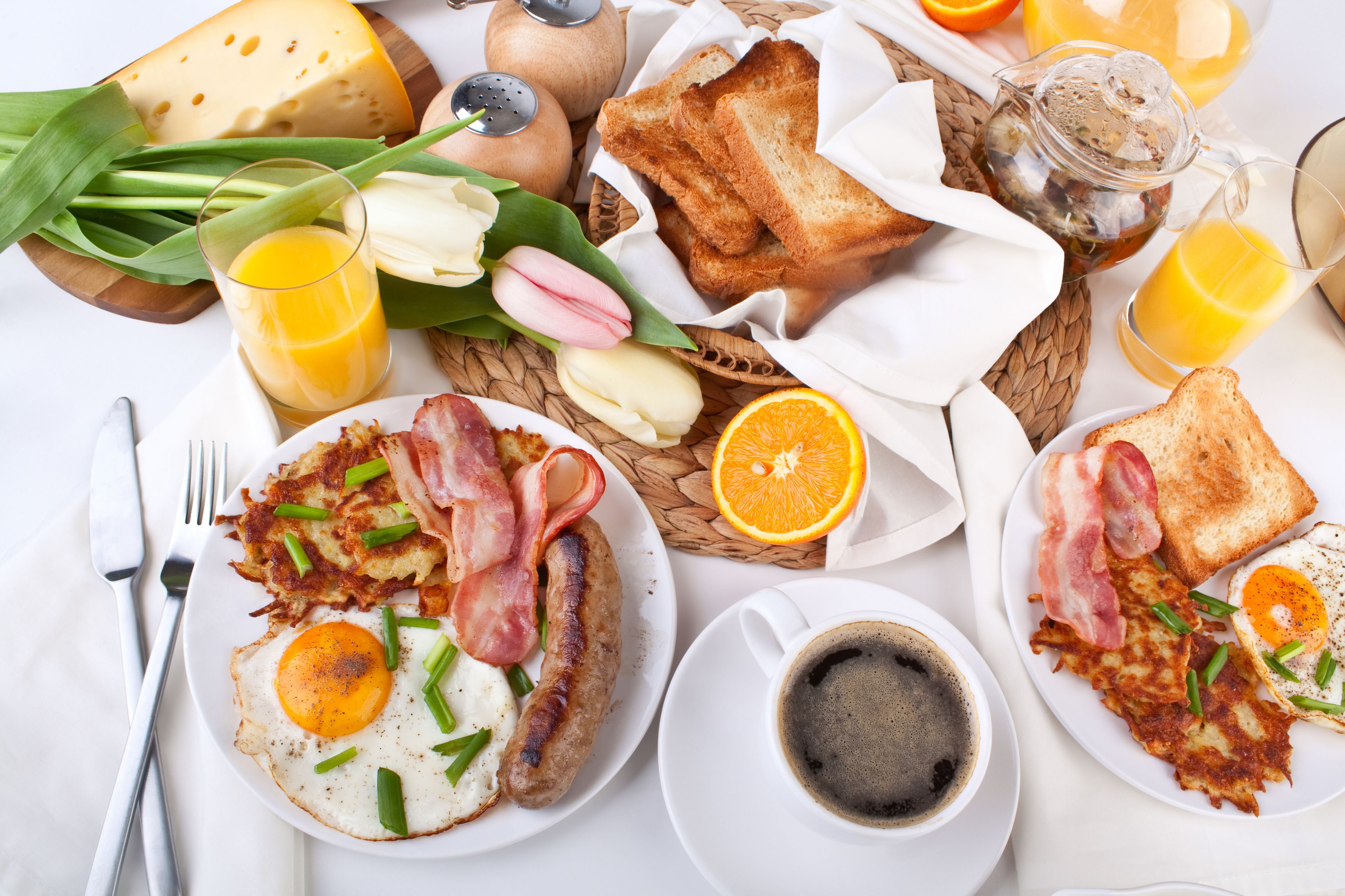 Un copieux petit-déjeuner composé d’œufs, de bacon, de saucisses, de pain grillé et de jus d’orange.