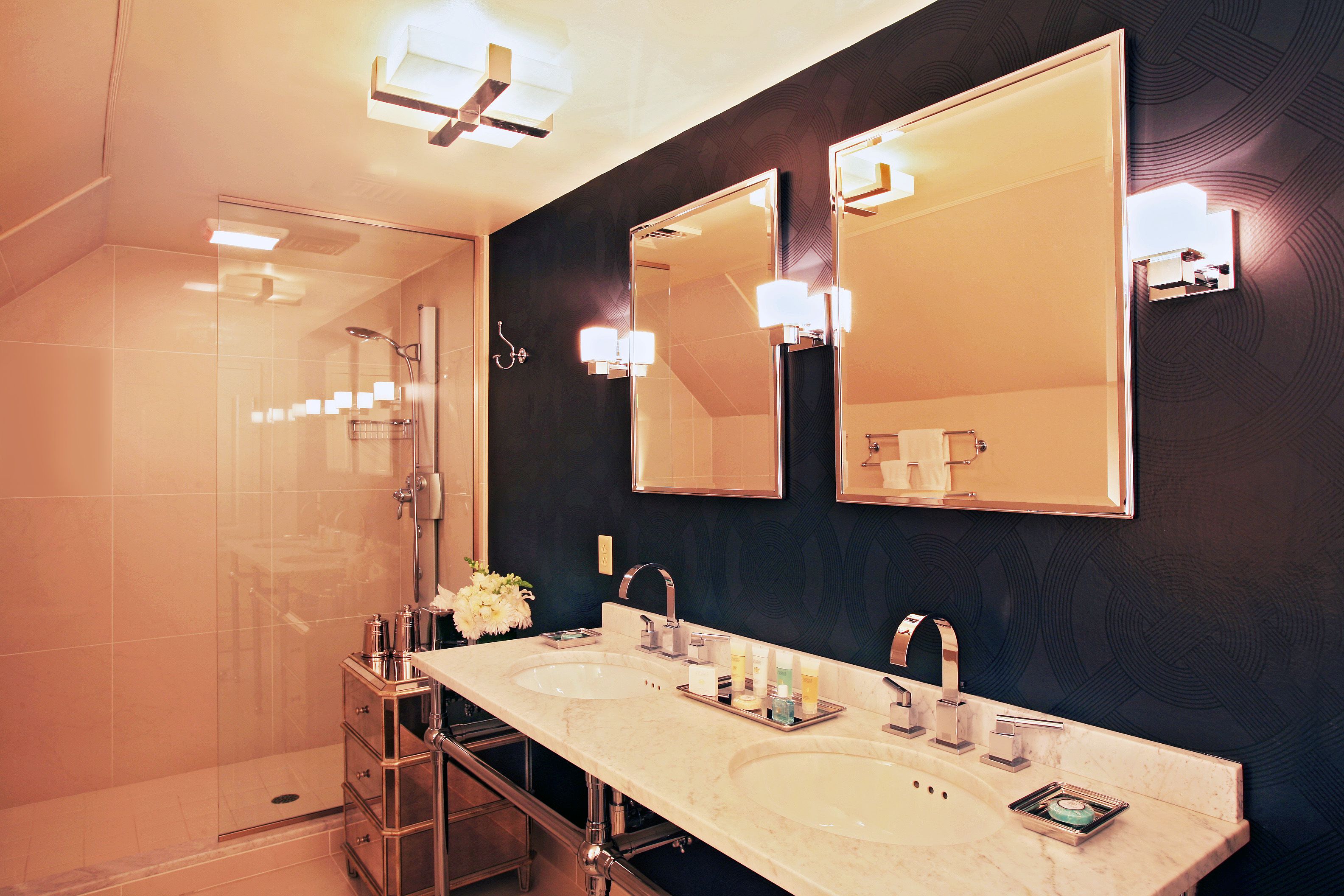 A modern bathroom with two sinks, a large mirror, and a glass shower enclosure.
