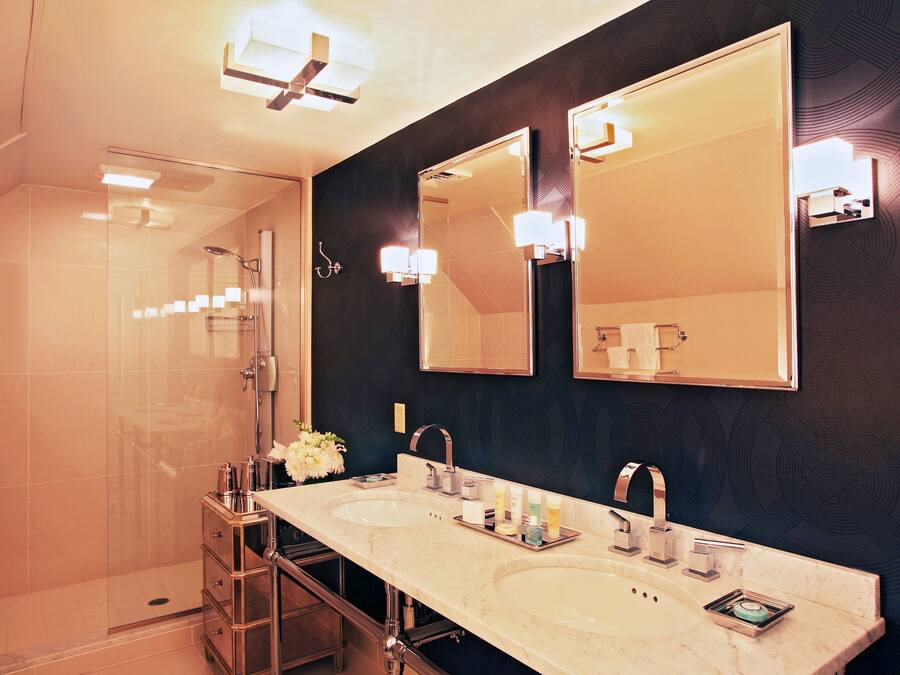 A modern bathroom with two sinks, a large mirror, and a glass shower enclosure.