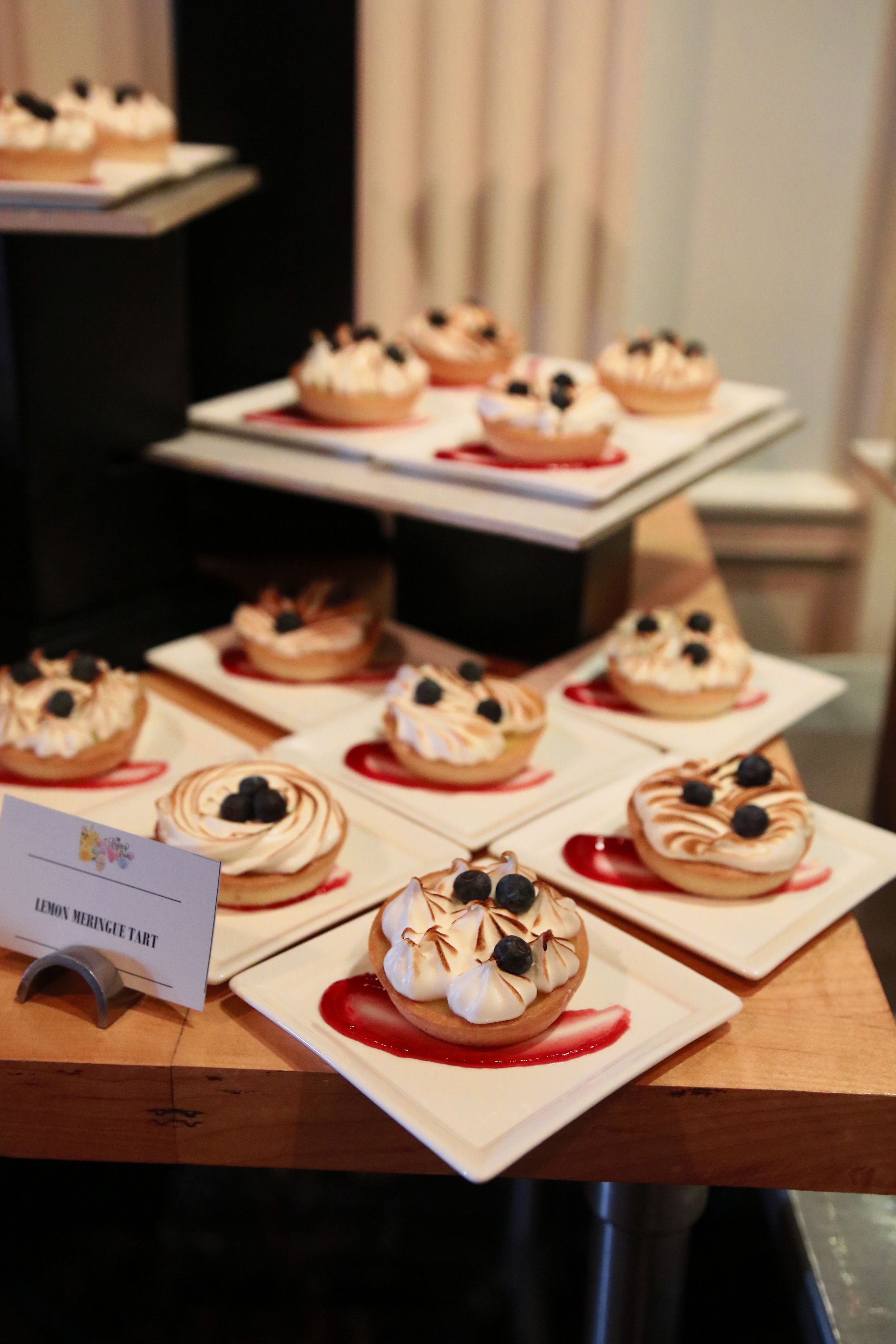 Uma variedade de tartes de limão e merengue dispostas sobre uma mesa de madeira.