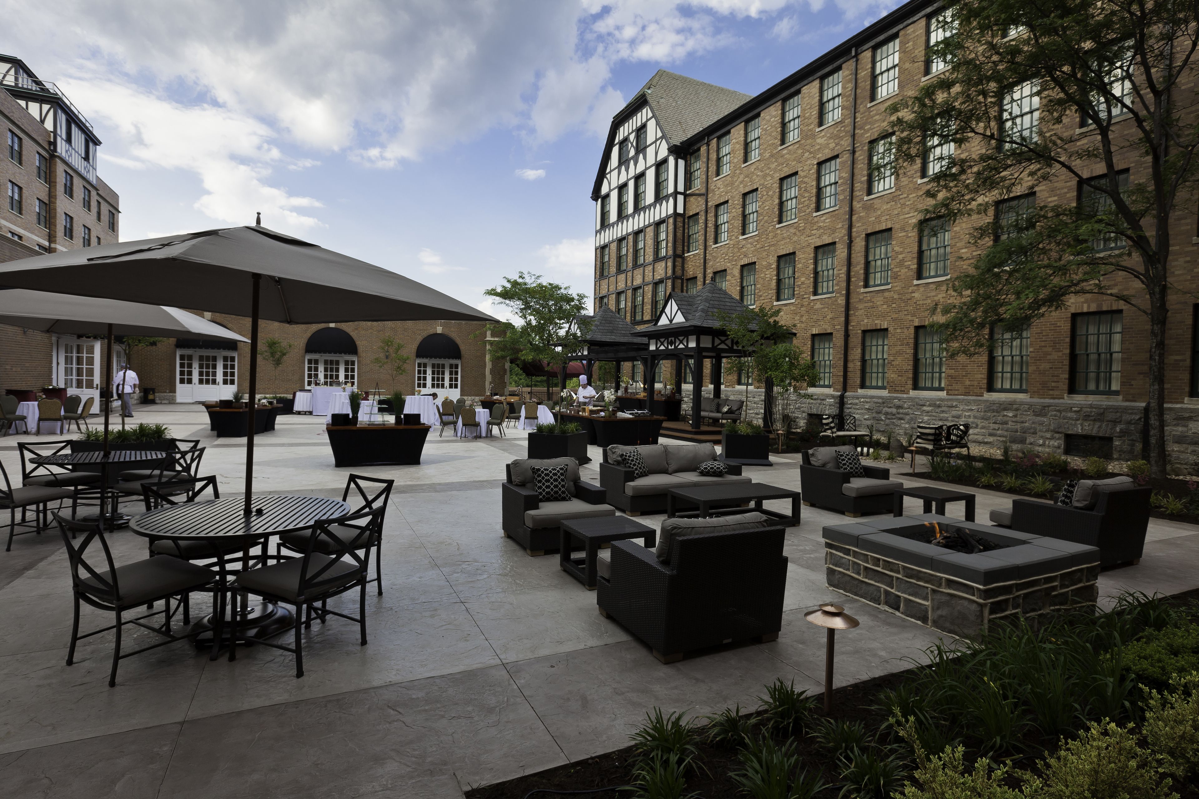 An outdoor patio area with round tables and chairs, sofas, and a fire pit.