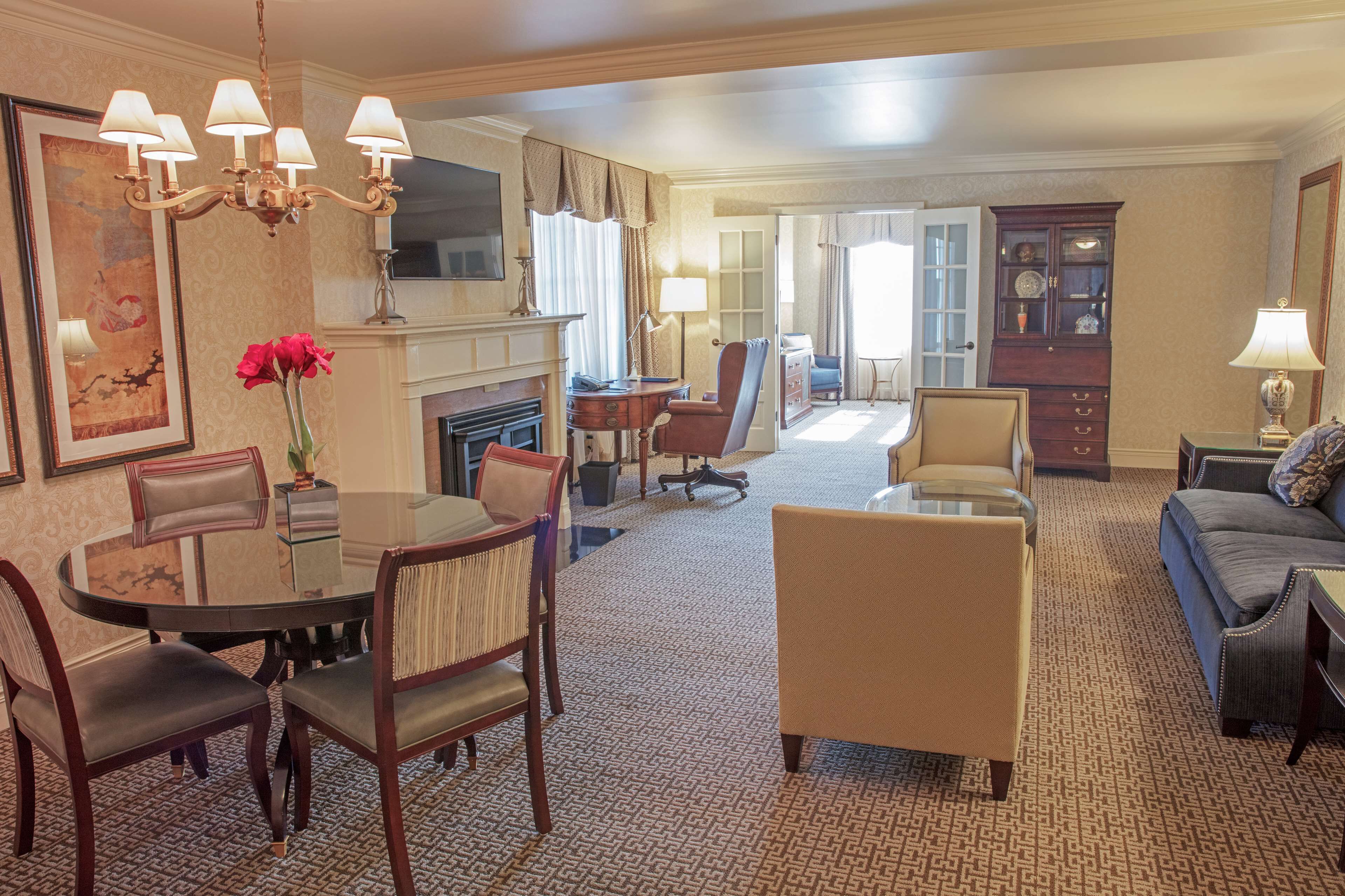 Une chambre d’hôtel comprenant un coin repas, un salon, une cheminée et une grande fenêtre.