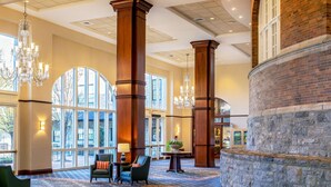 A spacious lobby with high ceilings, large windows, and a grand chandelier. - Hotel Roanoke & Conference Ctr, Curio Collection by Hilton  (Roanoke)