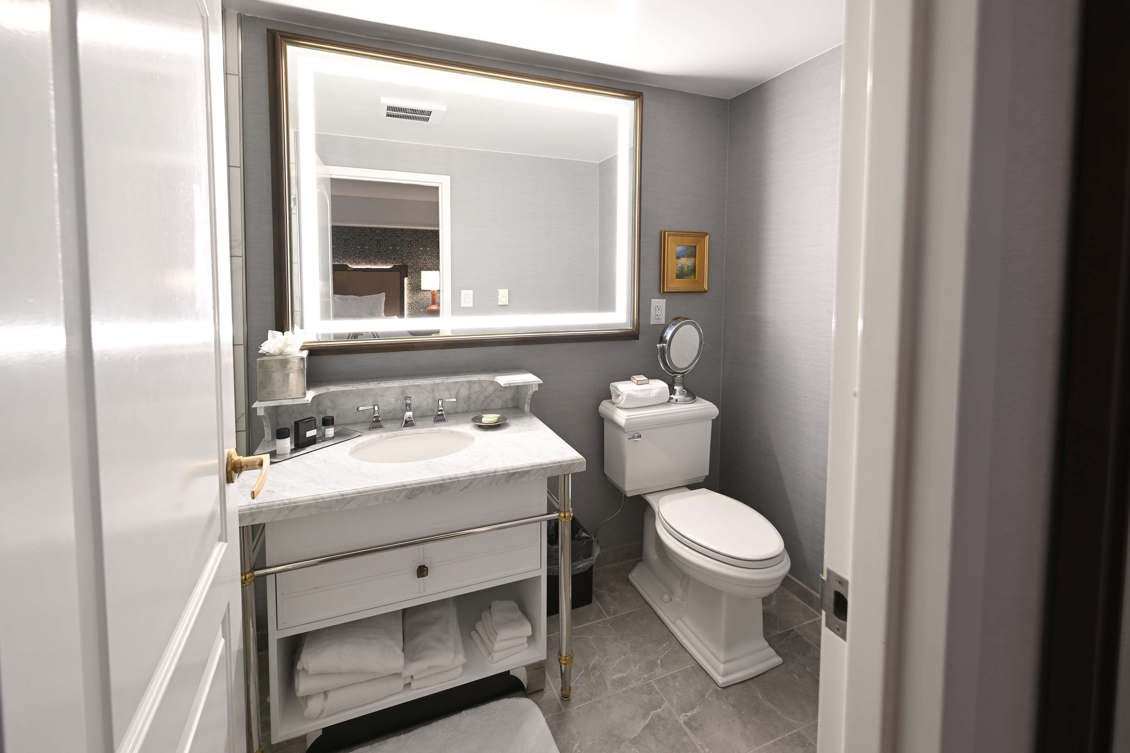 A modern bathroom with a large mirror, white fixtures, and a toilet.
