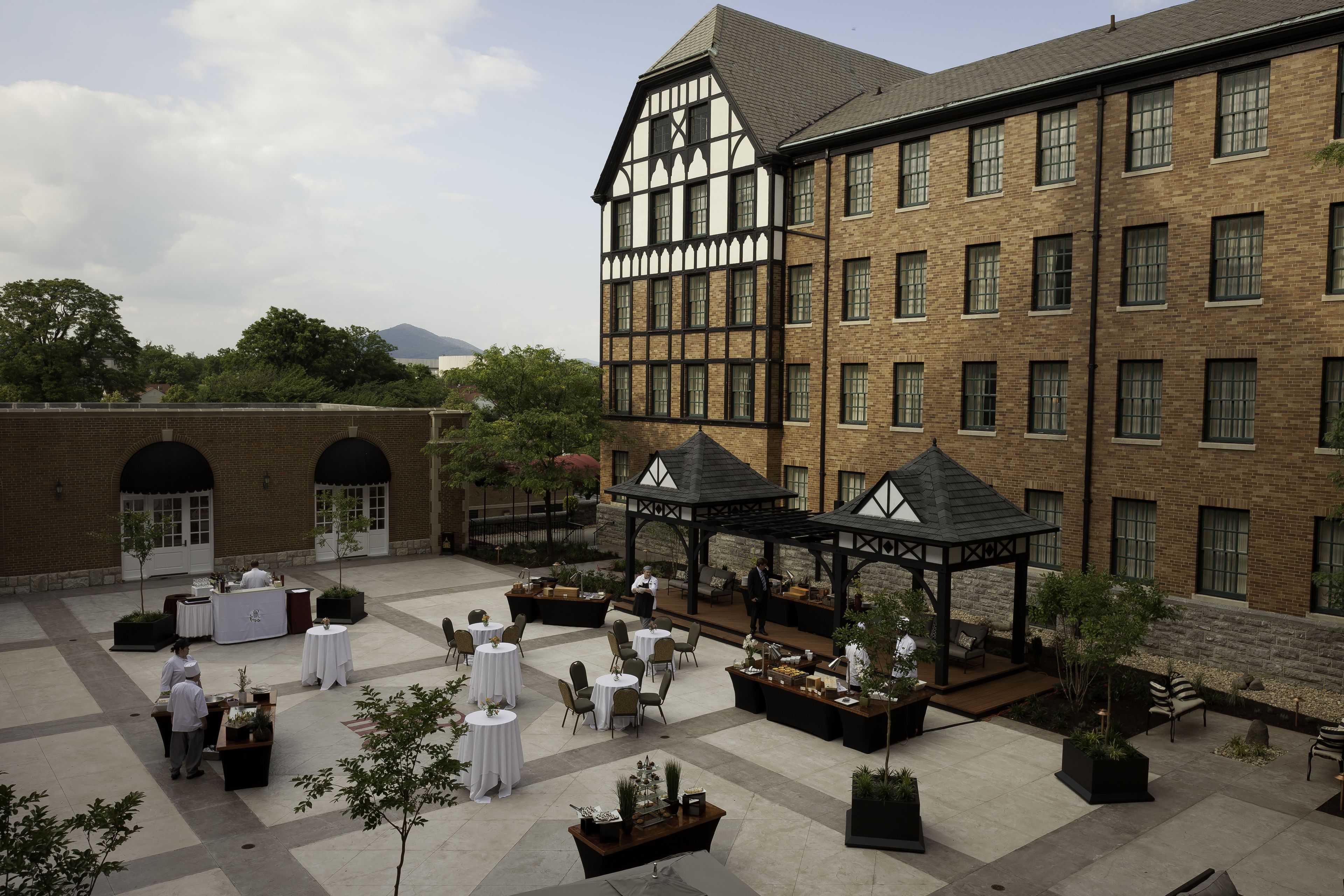 A courtyard with outdoor seating, a covered area, and a large building with a Tudor-style facade.