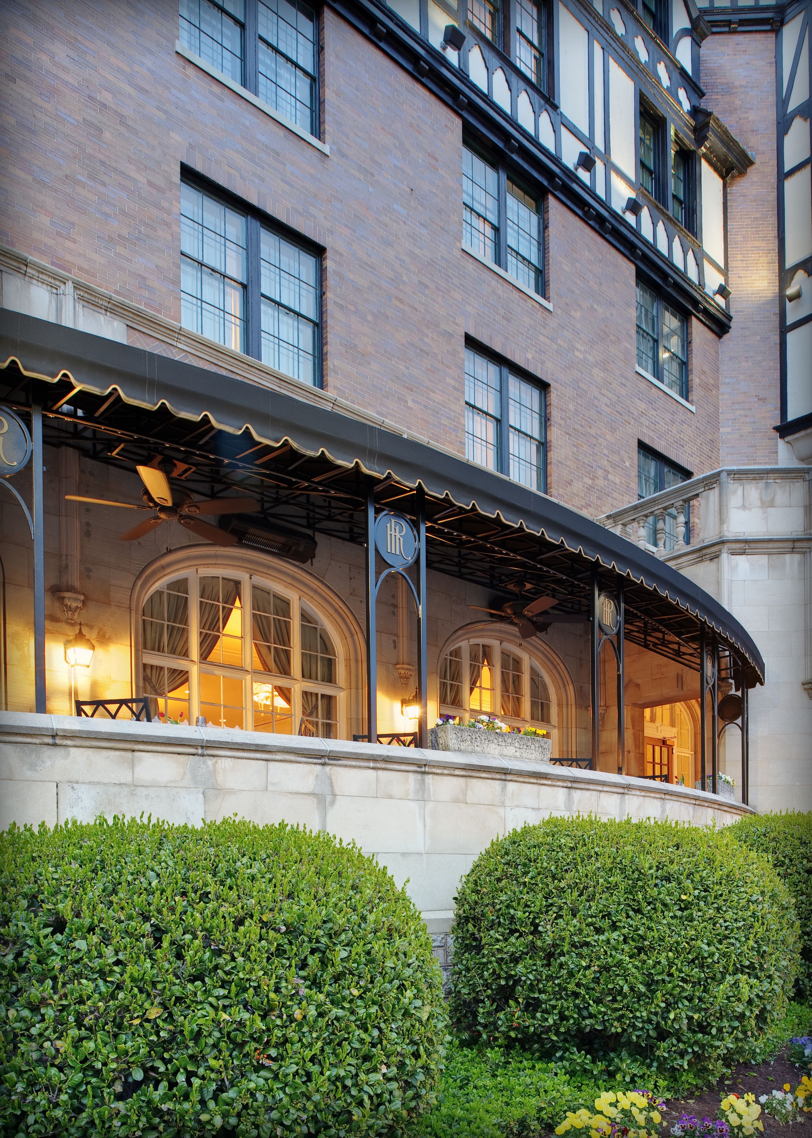 A brick building with large arched windows and a covered outdoor seating area.