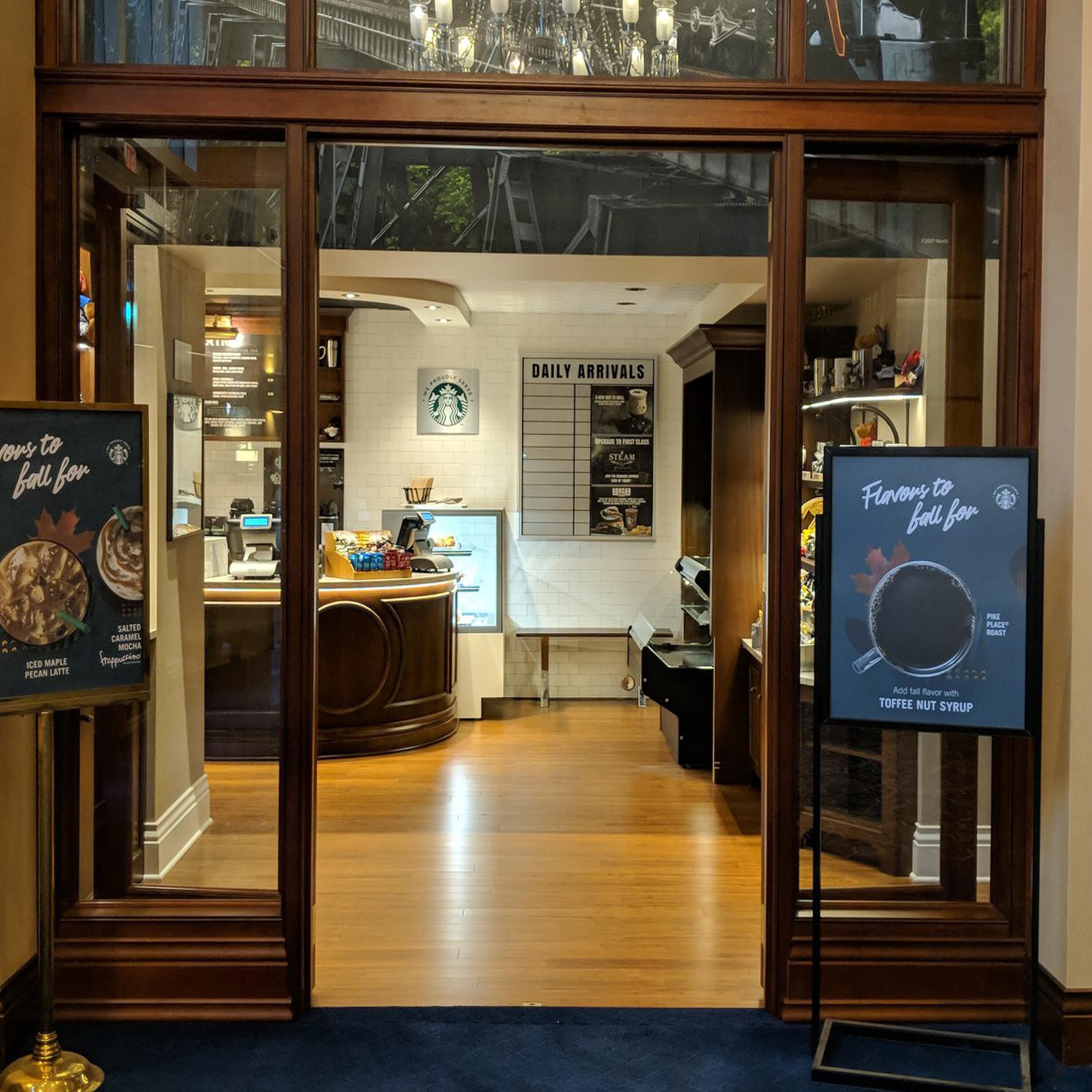 A Starbucks entrance with a sign for daily arrivals and a menu board.