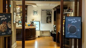 A Starbucks entrance with a sign for daily arrivals and a menu board.