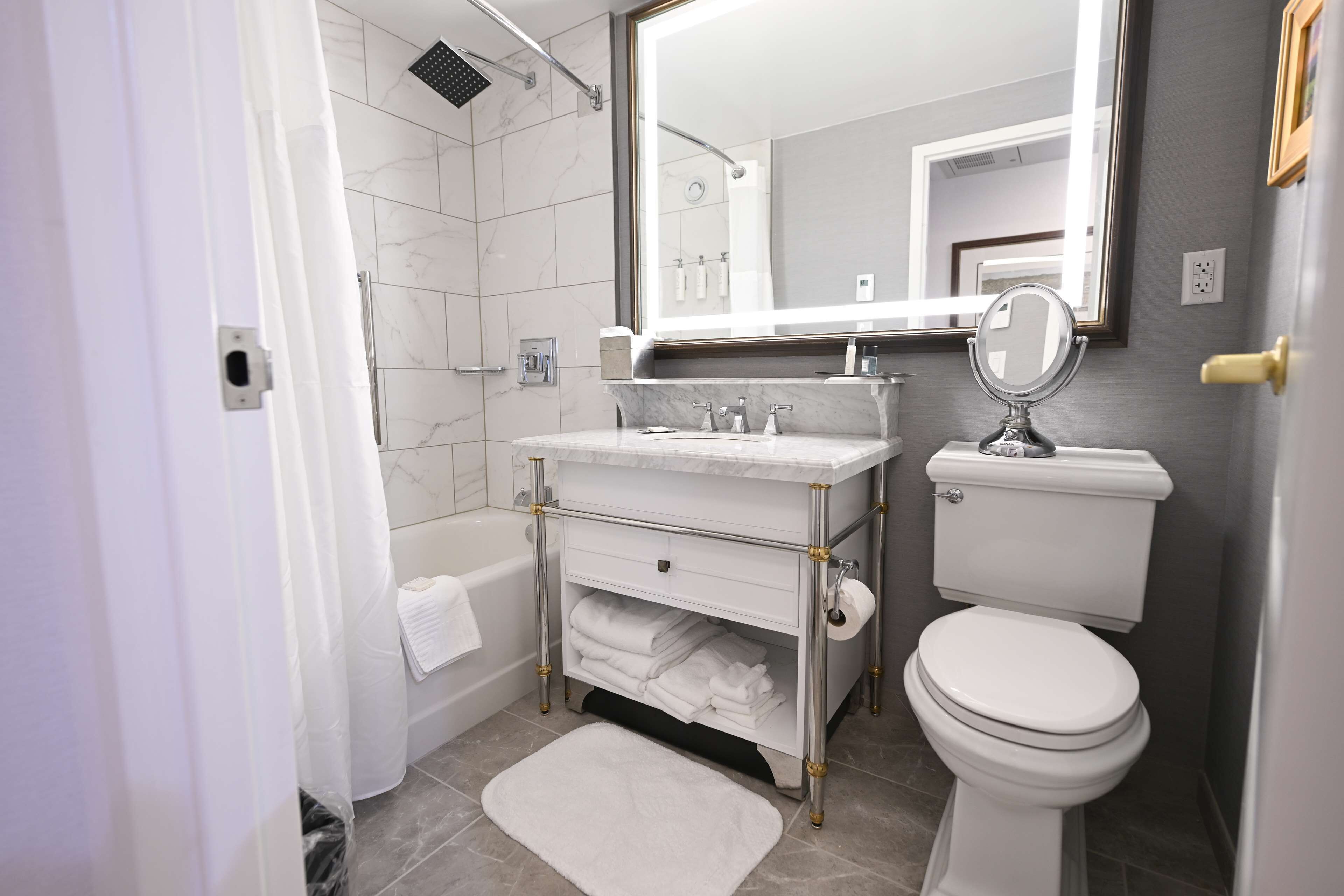 A modern bathroom with a marble sink, a toilet, and a large mirror.