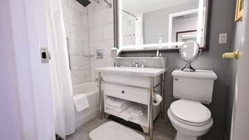Un baño moderno con lavamanos de mármol, inodoro y un espejo grande.